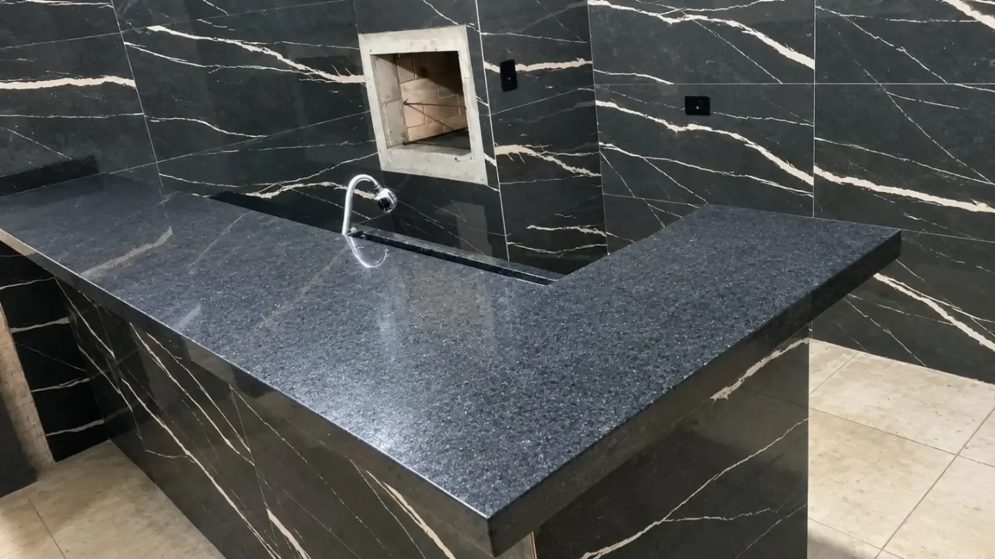Bancada em granito preto com nicho e parede revestida em mármore